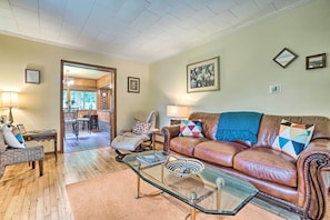 A living room with a brown leather sofa, glass coffee table, and a dining area with a wooden table and chairs. - 2-home Country Estate Near Clayton! 2 Hot Tubs (Clayton)