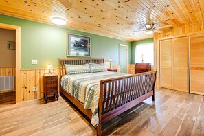 A wooden-paneled bedroom with a bed, a nightstand, a lamp, and a ceiling fan. - 2-home Country Estate Near Clayton! 2 Hot Tubs (Clayton)