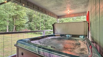 A hot tub in a covered outdoor area with a view of a forest.