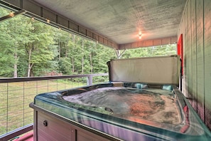 Ein Whirlpool in einem überdachten Außenbereich mit Blick auf einen Wald.