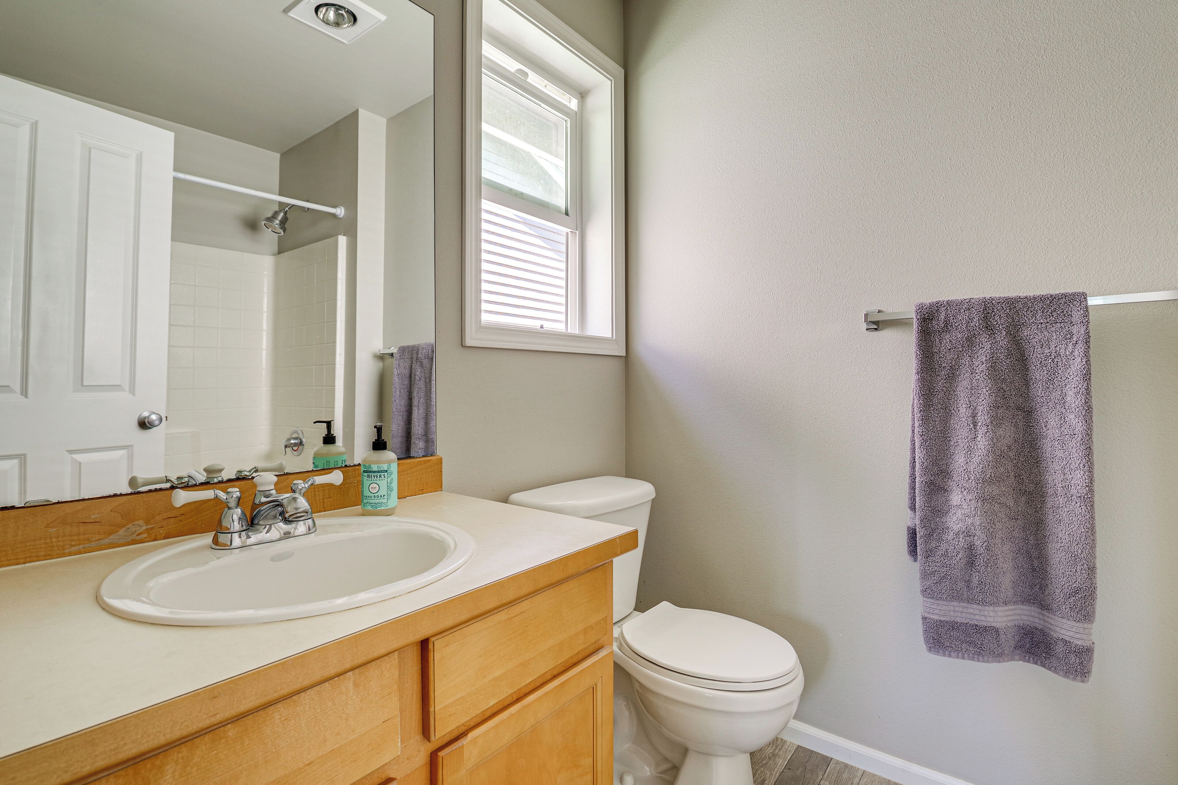 A bathroom with a white sink, wooden vanity, a toilet, and a towel rack.