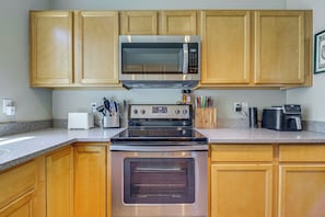A kitchen with wooden cabinets, a stainless steel microwave, a toaster, and a coffee maker.