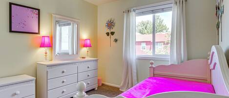 A bedroom with a bed, dresser, and window with curtains.