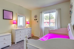 Ein Schlafzimmer mit Bett, Schminktisch und Fenster mit Vorhängen.