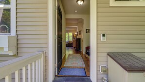 A hallway leading to a door with a doormat, a rug, and a light fixture on the ceiling. - Half Block to Train! South Beacon Hill Area Home (Seattle)