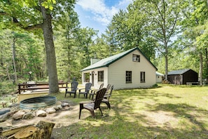 A cabin with a porch, outdoor seating, and a fire pit. - Angler Friendly! Pere Marquette Riverfront Retreat (Baldwin)