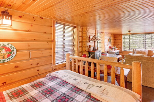 Un interior acogedor de cabaña con una cama de madera, una mesa de comedor y un sofá.