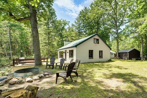 A cabin with a porch, outdoor seating, and a fire pit.
