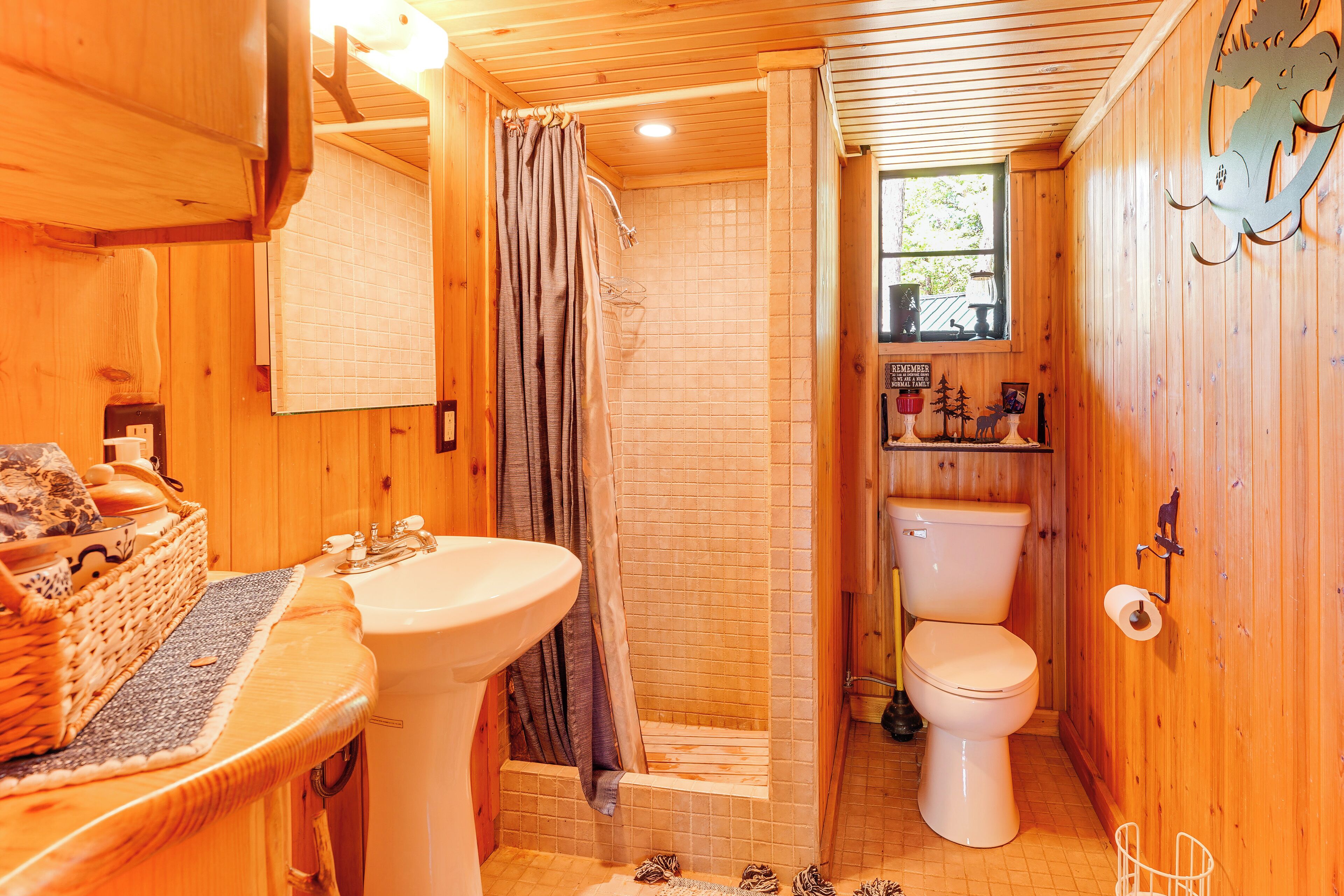 Een houten badkamer in een chalet, met douche, toilet en wastafel.