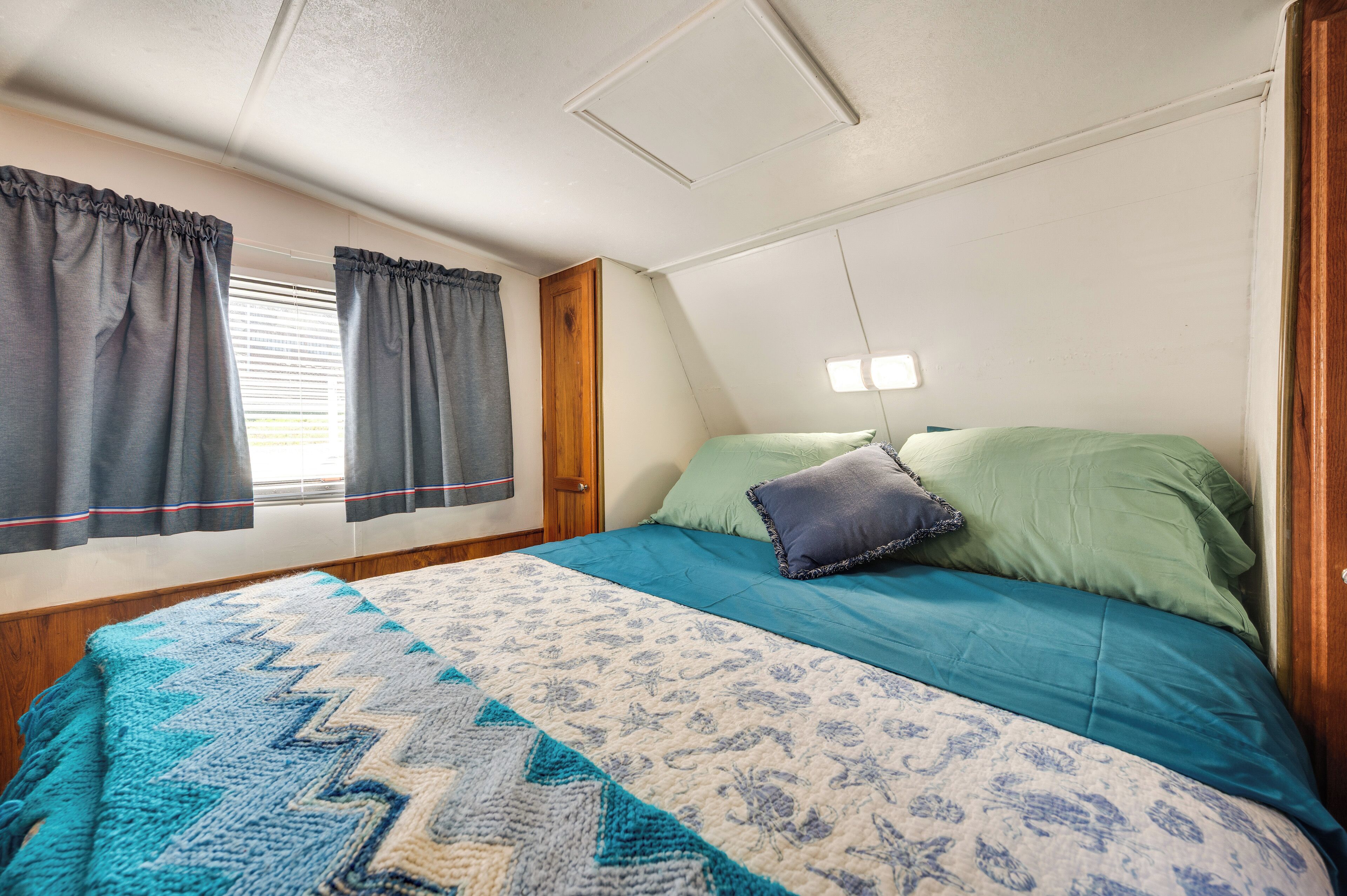 A bedroom with a bed, curtains, a window, and a ceiling light.