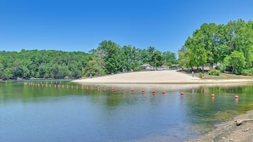 Un lac bordé d’une plage de sable, entouré d’une forêt dense et verdoyante.