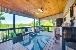 Una terraza techada al aire libre con ventilador de techo, una parrilla y una zona de estar con alfombra.