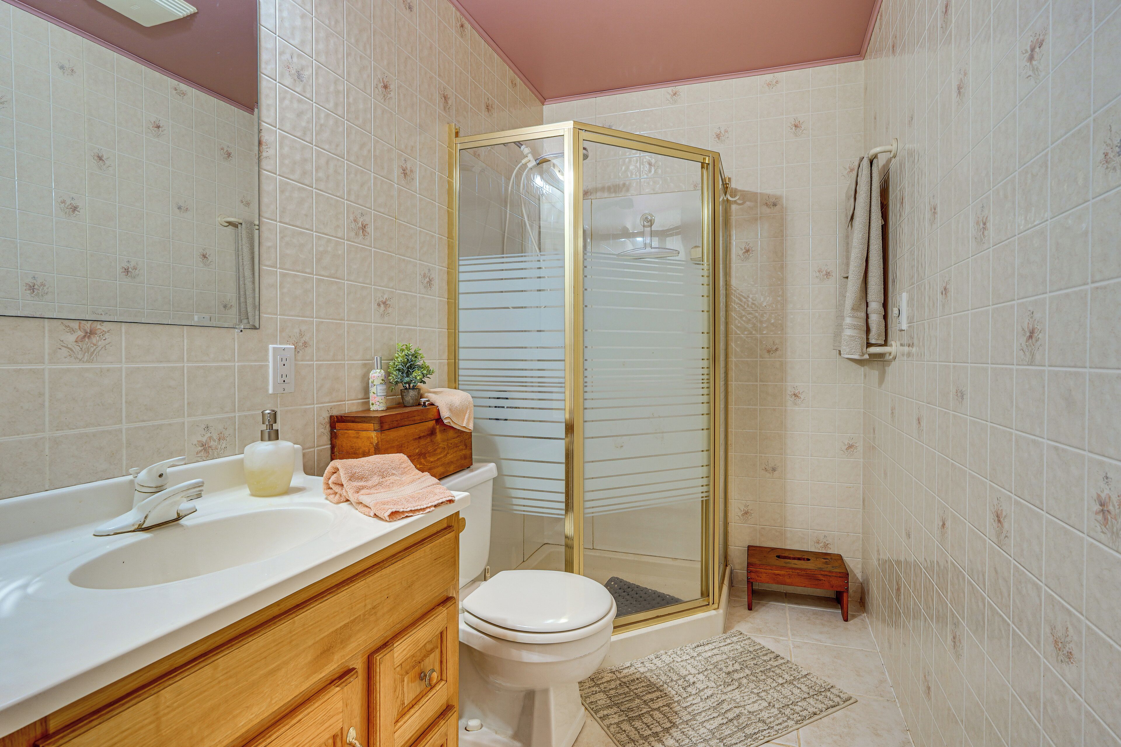 A bathroom with a shower, toilet, sink, and wooden vanity.