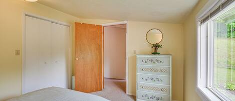 A bedroom with a bed, a dresser, a mirror, and a window.