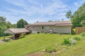 A single-story house with a covered patio, a lawn, and a wooden fence. - Mountain Retreat Near Cherry Springs w/ Game Room (Austin)