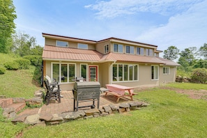 A two-story house with a patio, a grill, and a table. - Mountain Retreat Near Cherry Springs w/ Game Room (Austin)