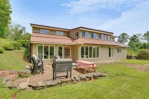 Ein zweistöckiges Haus mit Terrasse, Grill und Tisch.