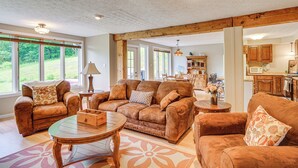 En rummelig stue med lædersofaer, et sofabord og et spiseområde med træmøbler.