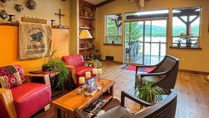 Ein gemütliches Wohnzimmer mit einer roten Ledersofa, einem Holztisch und einem großen Fenster mit Blick auf eine schöne Landschaft.
