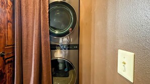 Lavadora y secadora integradas en la pared, con puerta de madera y un interruptor de luz en la pared.