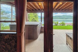 Uma porta de madeira que dá para um quarto com vista para um lago e montanhas.