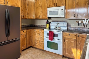 A kitchen with wooden cabinets, a stainless steel refrigerator, a microwave, and an oven. - Waterfront Gem on the River! Hot Tub & Boat Dock! (Priest River)