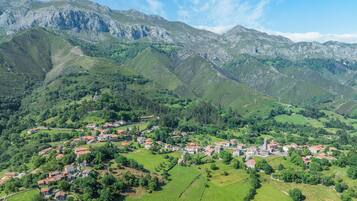 Un pueblo montañoso con casas tradicionales y una iglesia, rodeado de vegetación exuberante y terreno rocoso.