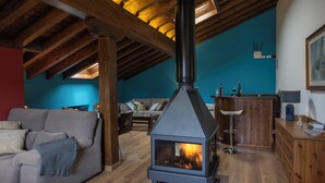Una sala de estar acogedora con una chimenea de leña, un sofá, una mesa de centro y un comedor con un aparador de madera y una lámpara.