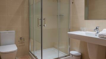 A modern bathroom with a glass-enclosed shower, a toilet, and a sink with a mirror above it.