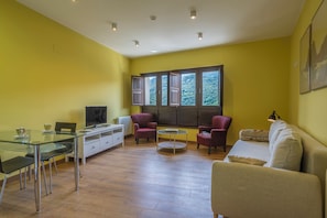 A living room with a glass table, two armchairs, a sofa, and a TV. - La Posada del Vencejo (Penamellera Alta)