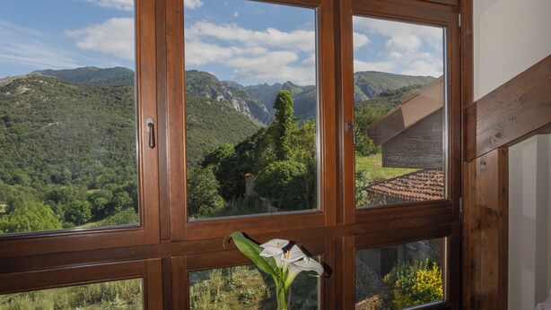 Una habitación con ventanas amplias, una mesa con un jarrón y dos sillas.