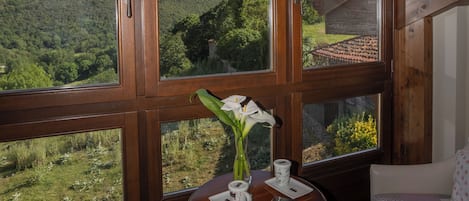 Una habitación con ventanas amplias, una mesa con un jarrón y dos sillas.