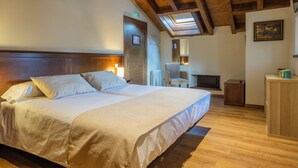 Un dormitorio con una cama grande, vigas de techo de madera, un tragaluz, un escritorio pequeño y una silla.