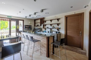 A modern kitchen with a bar area, bar stools, and a wooden door.