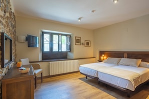 Ein Schlafzimmer mit einem großen Bett, einem Schreibtisch mit Stuhl, einem Fenster und einer Heizung.