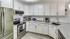 A modern kitchen with white cabinets, stainless steel appliances, a microwave, and a dishwasher. - 3BR Condo on the Bay w/ Pool and Perks (Rockport)