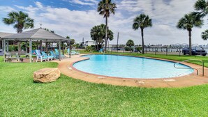 A swimming pool with lounge chairs, a gazebo, and palm trees. - 3BR Condo on the Bay w/ Pool and Perks (Rockport)