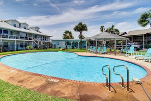 A swimming pool with lounge chairs, a gazebo, and a building with multiple stories and balconies. - 3BR Condo on the Bay w/ Pool and Perks (Rockport)