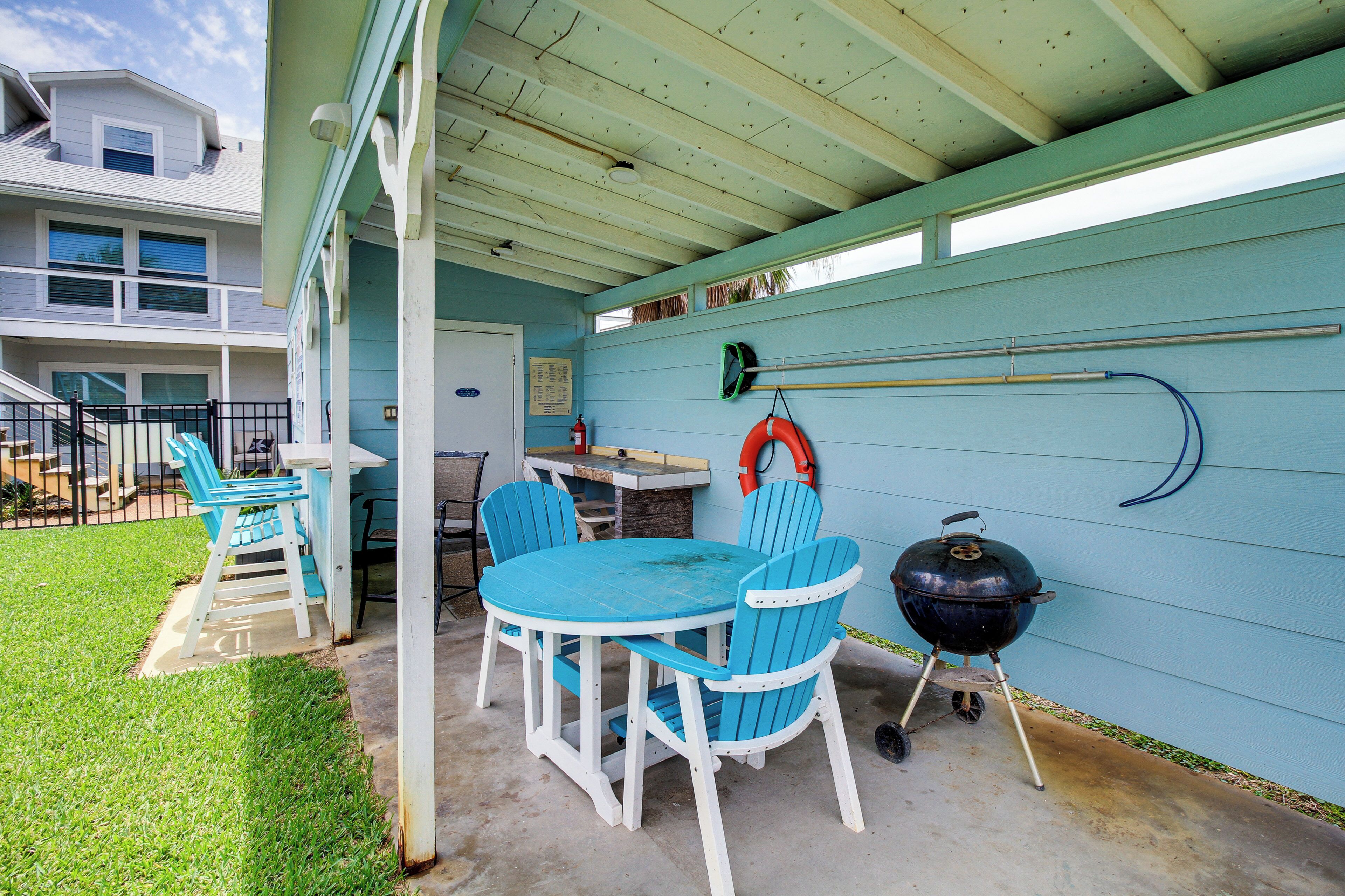Un patio couvert avec une table ronde et des chaises, un barbecue et un espace aménagé au bord de la piscine.