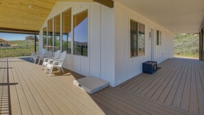 A covered deck with white chairs, a small table, and a blue storage box. - 2 Mi to Bear Lake! Group Getaway w/ Mountain Views (Garden City)