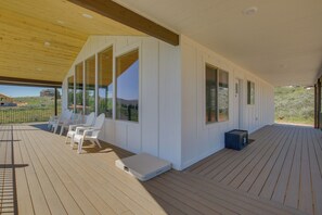 Eine überdachte Terrasse mit weißen Stühlen, einem kleinen Tisch und einer blauen Aufbewahrungsbox.
