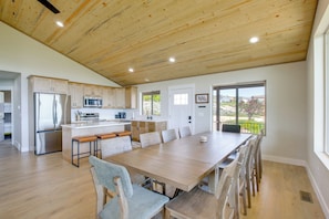 A modern kitchen with wooden cabinets, stainless steel appliances, and a large dining table.