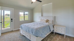 A bedroom with a bed, a nightstand, a ceiling fan, and a door leading to a balcony. - 2 Mi to Bear Lake! Group Getaway w/ Mountain Views (Garden City)