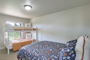 A bunk bed room with a window, a bed with a floral duvet, and a ceiling light. - 2 Mi to Bear Lake! Group Getaway w/ Mountain Views (Garden City)