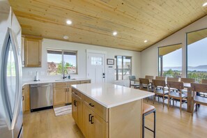 A modern kitchen with wooden cabinets, a stainless steel refrigerator, and a large island.