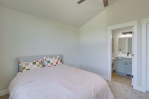 A bedroom with a bed, a headboard, a bathroom with a sink and mirror, and a door leading to another room. - 2 Mi to Bear Lake! Group Getaway w/ Mountain Views (Garden City)