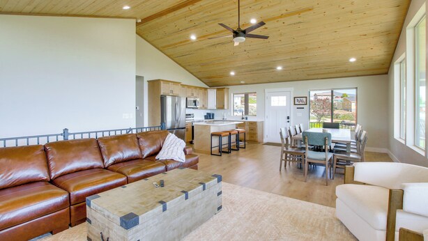 A spacious living area with a leather sofa, a wooden coffee table, and a dining area with a table and chairs. - 2 Mi to Bear Lake! Group Getaway w/ Mountain Views (Garden City)