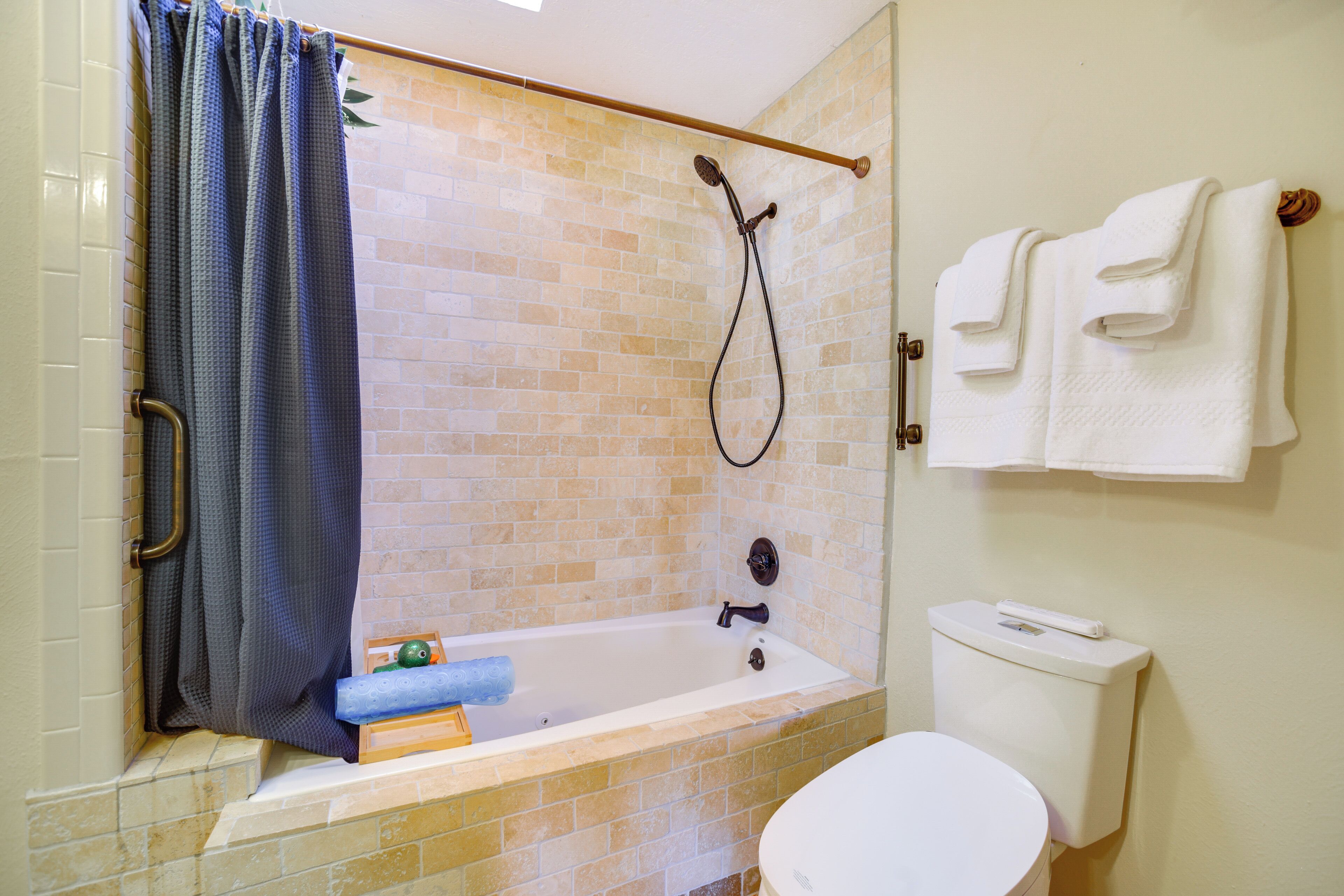 A bathroom with a bathtub, shower, toilet, and towel rack.