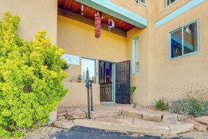 A building with a stone pathway leading to a door, a hanging decoration, and a small garden area.