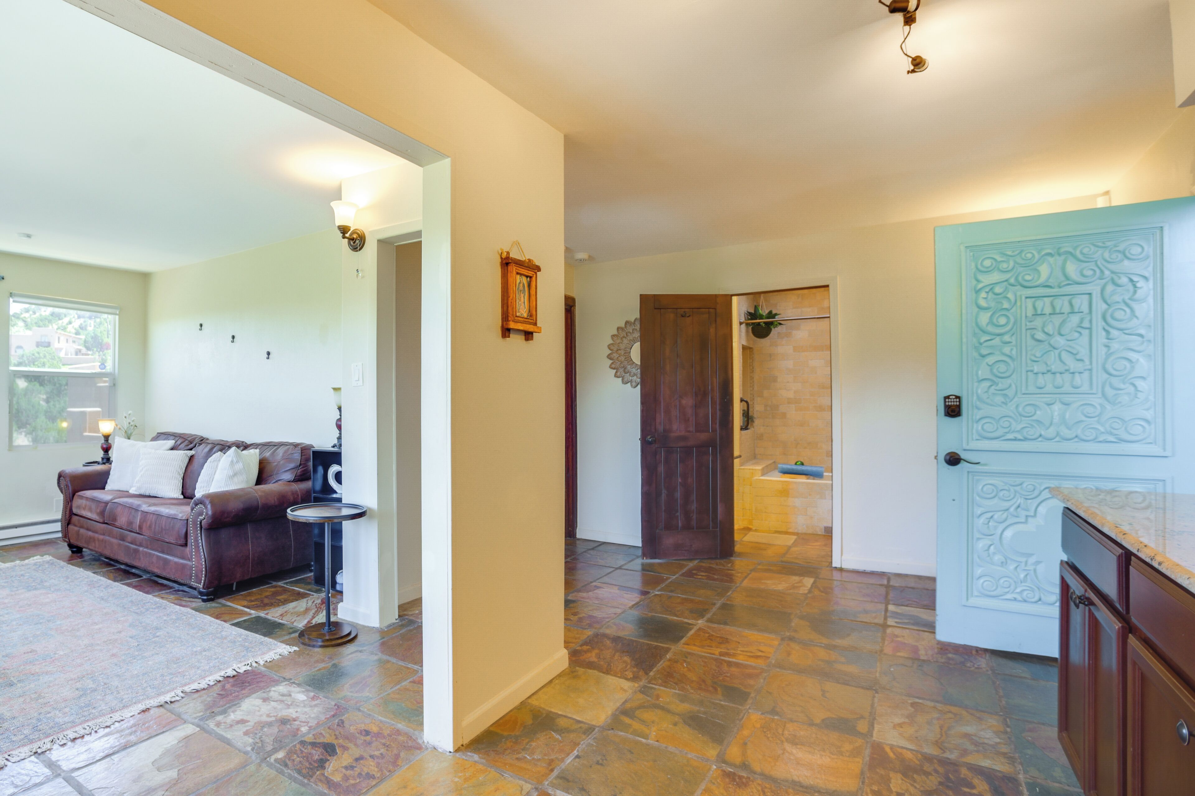A spacious living area with a brown leather sofa, a small round table, and a patterned rug.
